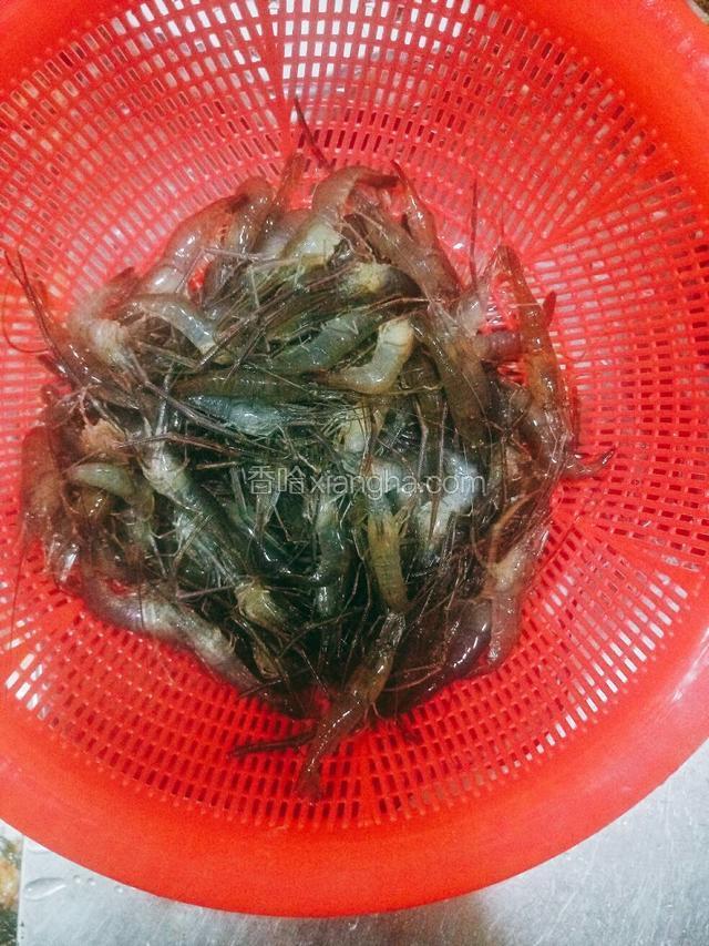准备河虾，剪去虾脚虾须也可不剪，先清洗几次，然后倒入塑料筐中空干水