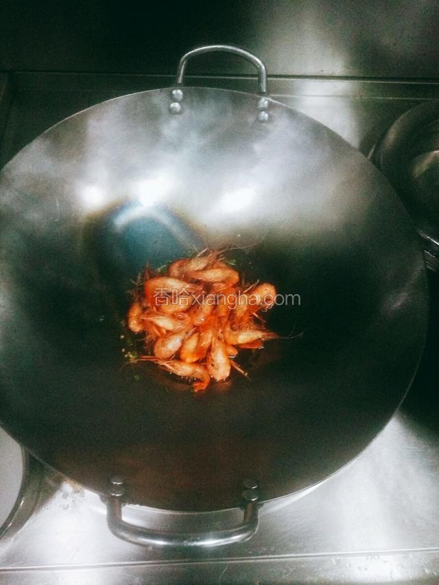 加入黄酒、糖、生抽（按辅料中的量添加），倒入几滴麻油，烧开倒入炸好的虾翻炒，待锅中汤汁收干为止，倒入一点点醋翻炒两下，则出锅装盘